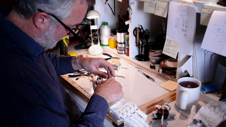 A man working on electronics at a workbench